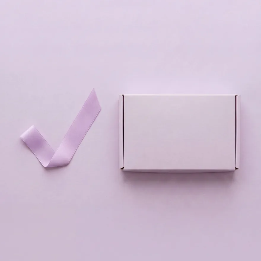 A discreet cervical screening kit box beside a ribbon tick