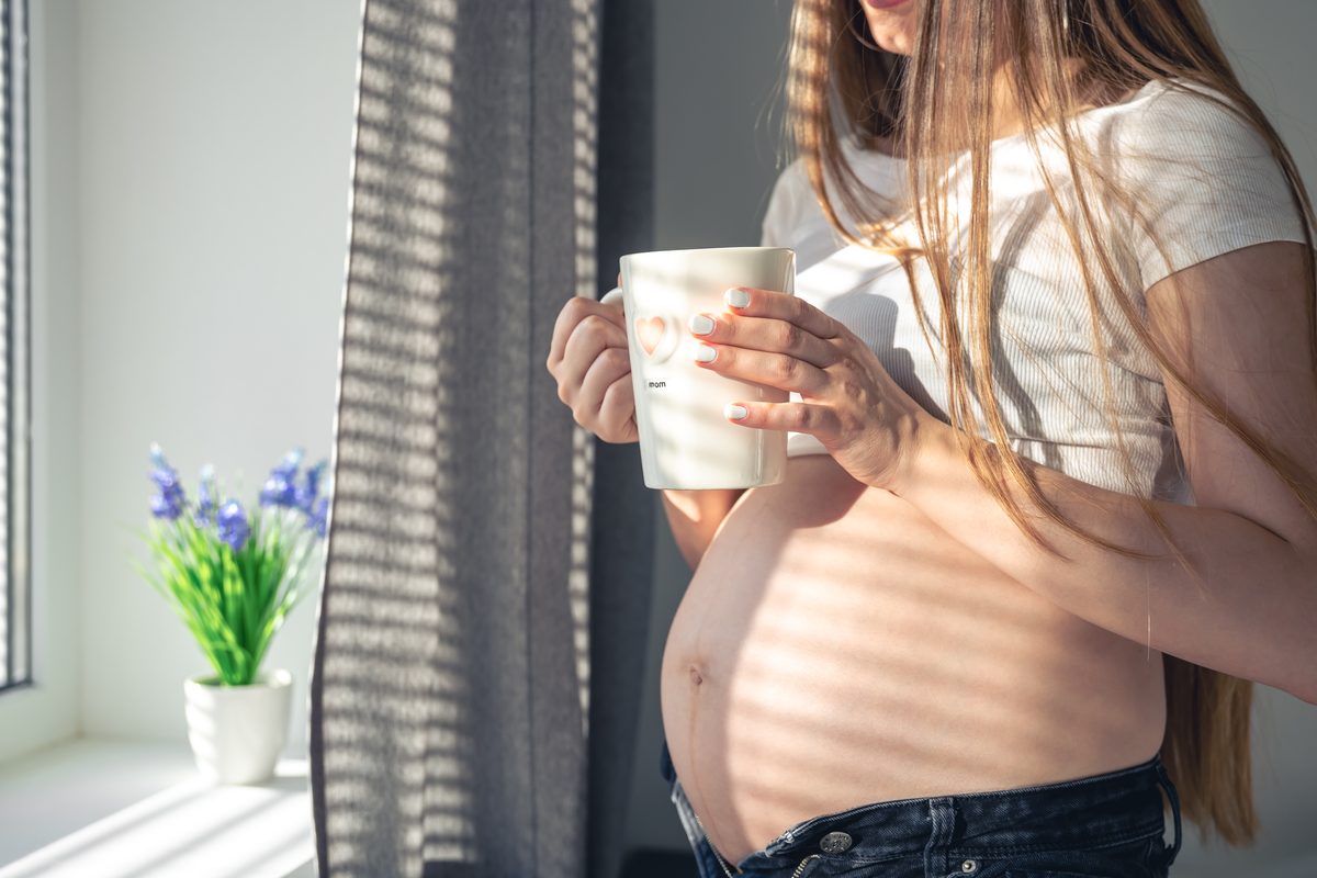 A pregnant woman resting a hand on her belly at home